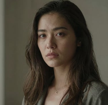 A smiling woman with beautifully waved hair holding the Curlina tool in a cozy, sunlit room.