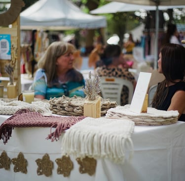 Tapices de macramé hechos a mano y decoración bohemia exhibidos sobre una mesa blanca en un mercado 