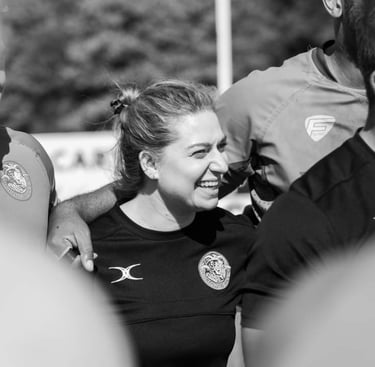 Fleur laughing in a rugby huddle.