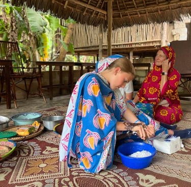 Tourist learning how to crack mature coconut (nazi) with traditional tools during a luxury Zanzibar spice tour with local