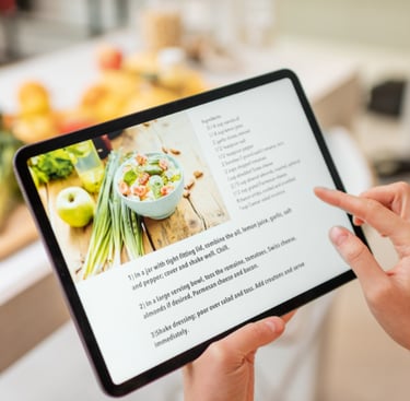 Person using a tablet to display a recipe. Ingredients are blurred out in the background