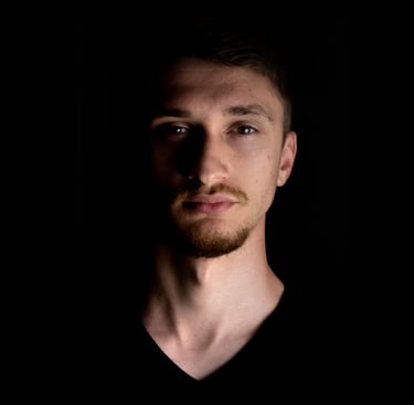 Close-up shot of music artist Valah's face in the dark, illuminated by dramatic lighting.