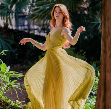 Ragazza in mezzo alla vegetazione con un abito dorato svolazzante