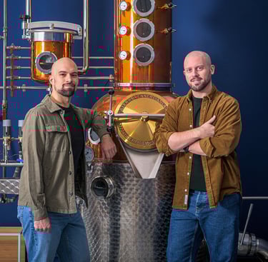 master distiller e designer in posa professionale davanti ad un alambicco di rame e acciaio