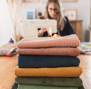séance photo professionnelle d'une couturière en train de coudre avec ses tissus devant