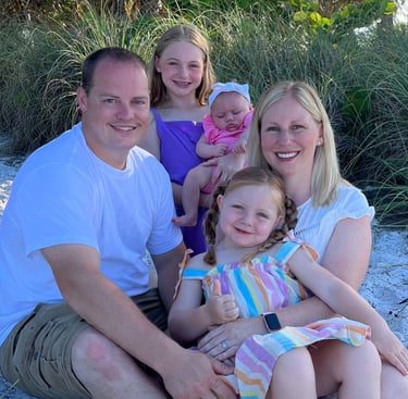 a family of four children sitting on a sandy beach
