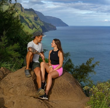 a man and woman sitting on a rock in hawaii