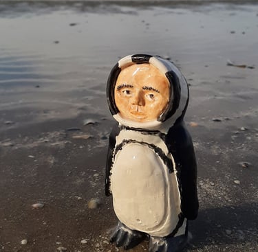 a ceramic figurine in a penguin suit on the beach