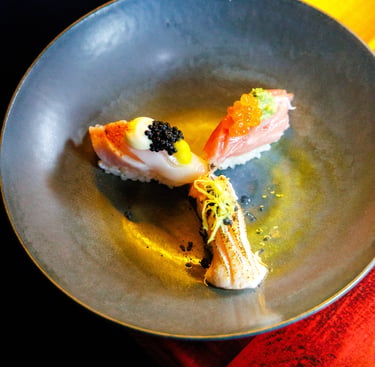 Três niguiris de sushi premium com ovas e especiarias servidos em um prato escuro no Okone Sushi Nikkei Porto.