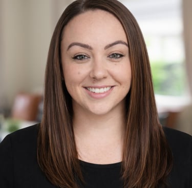 Professional headshot of a smiling woman with straight brown hair wearing a black shirt.