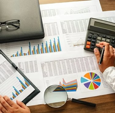 a person sitting at a desk with a calculator and a magnifying