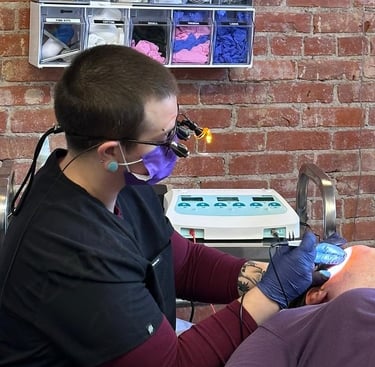 Sam, a skilled practitioner, with specialized eyewear on, treating a client with needle epilation