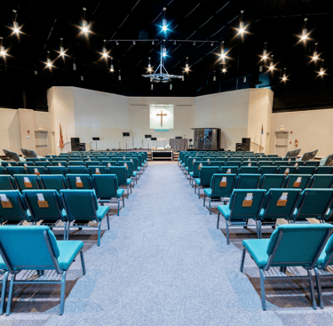Intérieur de l'église avec des chaises, une estrades avec des micros 