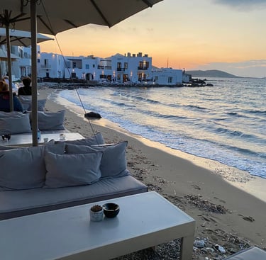 a couch with pillows and a coffee table on a beach at sunset