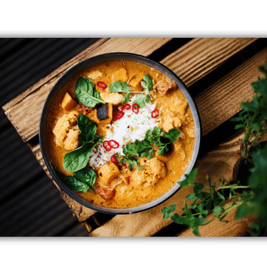 a bowl of food with a wooden table and a potted plant