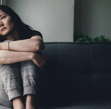 a sad woman sitting on a couch in a living room