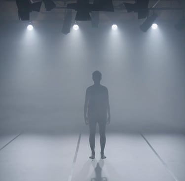  Performer standing under multiple stage lights in fog – film still from Lingua Materna by Tina Bikic