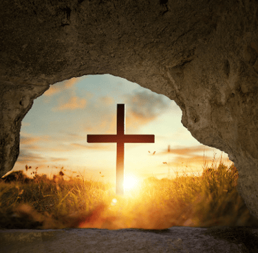 Looking through opening in stone at a cross in front of sunset