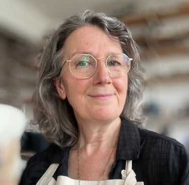 Ceramic artist Anna Butler looking to camera, in her North London ceramic studio