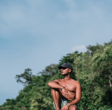 a man sitting on a rock with a hat on