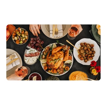 A festive holiday dinner table spread with roasted whole chicken, seasonal vegetables, wine, and appetizers.
