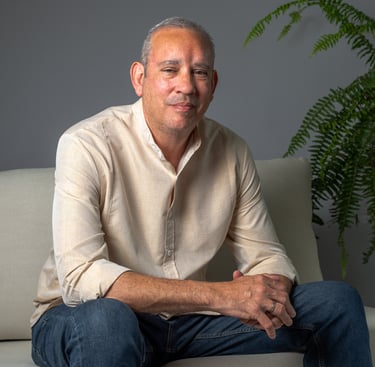 a man sitting on a couch with a plant in the background