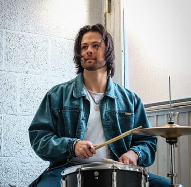 a man in a blue jacket playing drums