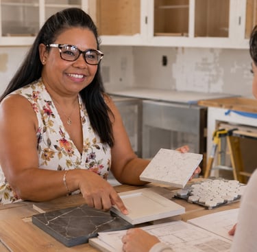 A smiling interior designer shows a client material samples for a modern kitchen remodel project.