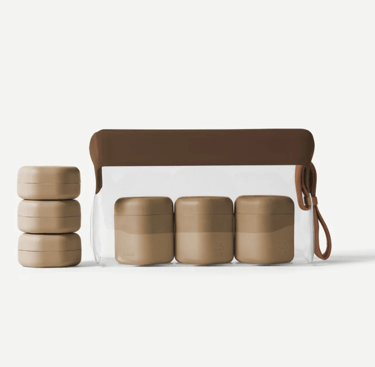 Set of tan refillable magnetic travel capsules and a clear toiletry bag for organized packing.