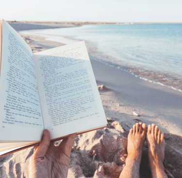 a person reading a book on a beach