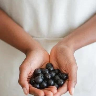 une femme tenant une poignée de myrtilles dans ses mains.