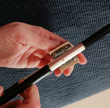 A person holding a rosin in their hand while rosining their bow