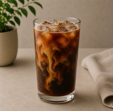 Iced coffee with cream swirls in a tall glass with ice cubes on a neutral table.