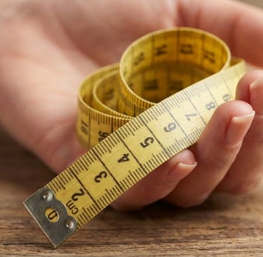 Main de femme tenant un mètre ruban pour mesurer la taille d’une bague