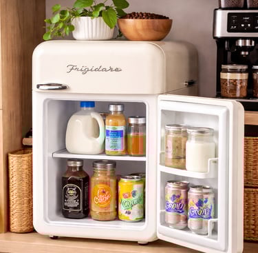 Open Frigidaire retro mini fridge stocked with beverages and milk in a home coffee station.