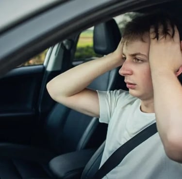 A stressed driver holding his head in frustration while sitting in a car seat after a breakdown.