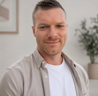 Professional headshot of a smiling man with short hair wearing a beige button-down shirt.