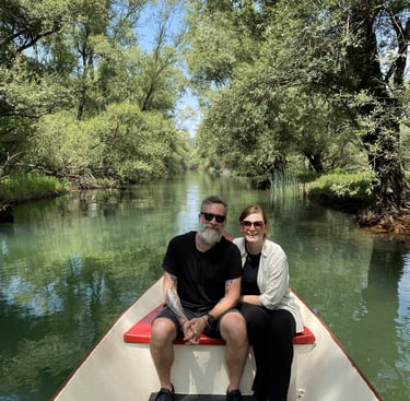 A couple taking a scenic boat tour on a clear green river surrounded by lush summer trees montenegro