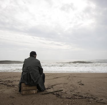 Homme de dos, assis devant le roulement desvaguessur une plage deserte