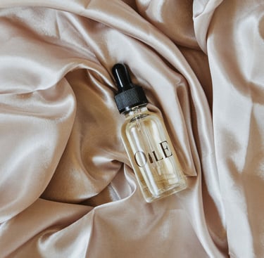 Luxury facial oil dropper bottle resting on folded champagne silk fabric.