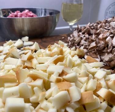 Chopped smoked cheese, sliced mushrooms, and ground meat prepared for cooking on a wooden board.
