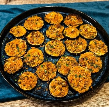 Crispy baked eggplant rounds topped with seasoned breadcrumbs and herbs on a dark serving platter.