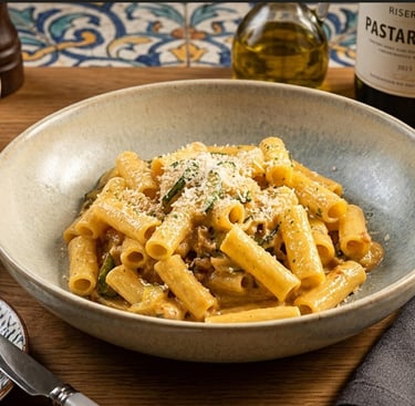 Creamy rigatoni pasta with zucchini and parmesan cheese served in a ceramic bowl on a rustic table.