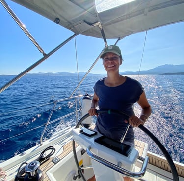 Stephanie Kabelin hat das Steuerrad in der Hand auf dem Segelboot