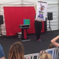 Magician performing a rabbit in a hat drawing trick on stage for a live audience.