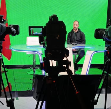 a man sitting at a table with a laptop and camera