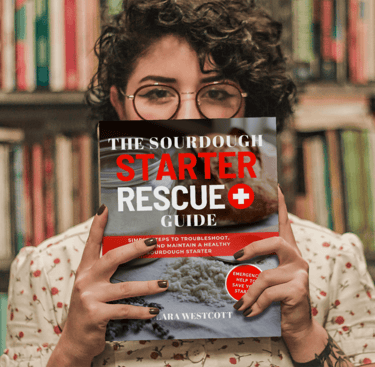 a woman holding a book in front of a bookshelf