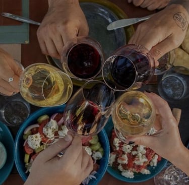 a group of people holding glasses of greek wine and toasting