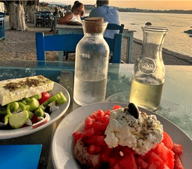 a table with a plate of greek mezzes and a bottle of white wine