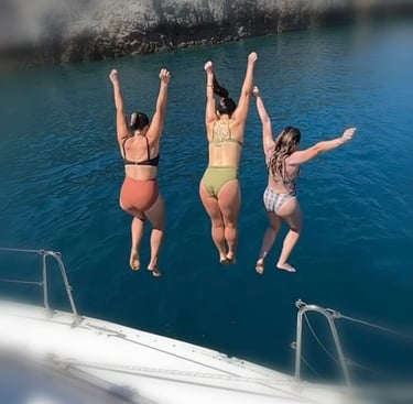three women jumping into the sea in chania in a boat